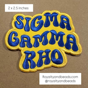May include: A yellow and blue embroidered patch with the text "SIGMA GAMMA RHO". The patch measures 2 x 2.5 inches. The text is in blue, with a yellow border. The patch also includes the website royaltyandbeads.com and the Instagram handle @royaltyandbeads.