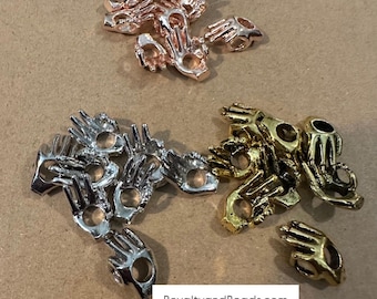 May include: A collection of small, hand-shaped metal beads in gold, silver, and rose gold. The beads have a hole in the center for stringing.