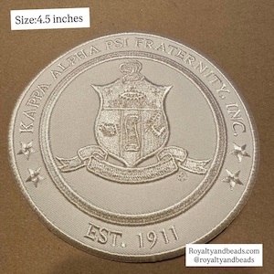 May include: A circular embroidered patch, 4.5 inches in diameter, featuring the Kappa Alpha Psi Fraternity crest. The design includes the fraternity name, crest, and the founding year, 1911. The patch is in shades of gray and white.