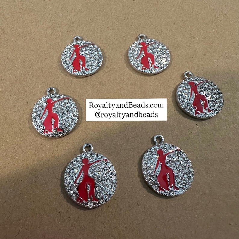 May include: Six silver charms with a red silhouette of a person dancing on a white background with clear rhinestones. RoyaltyandBeads.com @royaltyandbeads