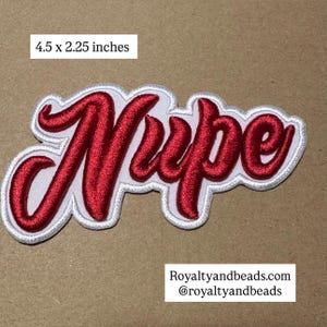 May include: Embroidered patch with the word "Nope" in red script lettering, outlined in white and gray. The patch measures 4.5 x 2.25 inches. The patch is on a tan background.
