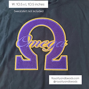 May include: A black sweatshirt with a large purple and gold embroidered Omega design. The embroidered design measures 10.5 x 10.5 inches. The word "Omega" is embroidered in a cursive font within the Omega symbol.
