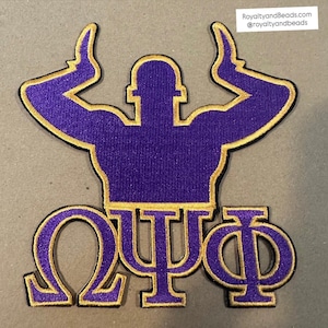 May include: A purple and gold embroidered patch featuring a stylized figure with raised arms above three Greek letters. The patch has a gold border and the text "RoyaltyandBeads.com @royaltyandbeads" in the upper right corner.