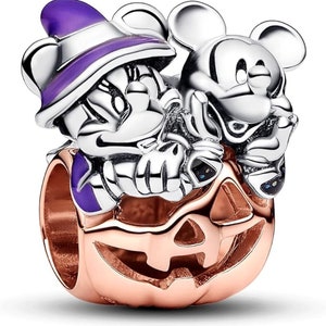 May include: A silver charm featuring Mickey and Minnie Mouse dressed in Halloween costumes, perched on top of a rose gold pumpkin.