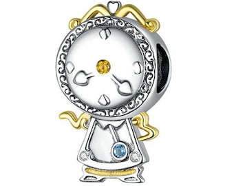 May include: A silver charm with a gold crown and wings. The charm features a face with a clock face and a yellow and blue gemstone.