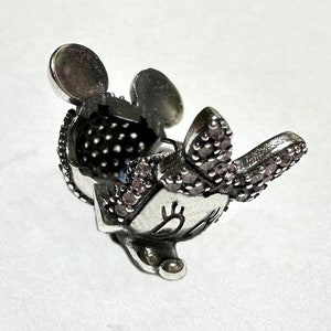 Puede incluir: Encanto de plata con un rat&oacute;n de dibujos animados con detalles de cristal rosa. El rat&oacute;n tiene orejas grandes, un lazo y una cara sonriente.