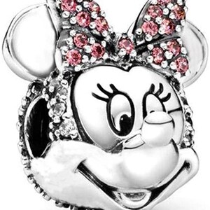Puede incluir: Un charm de plata con una representaci&oacute;n de dibujos animados de Minnie Mouse con un lazo rosa. El charm est&aacute; detallado con cristales brillantes de color rosa y transparente.