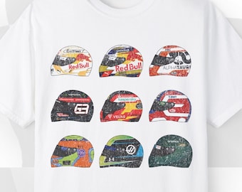 May include: White t-shirt with a graphic print of nine different racing helmets. The helmets are in various colors and designs, including red, blue, green, and yellow.