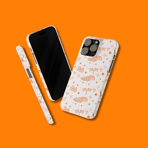 May include: Three phone cases with a white background and orange designs. One case has a black screen and the other two have a white background with orange racing car and checkered flag designs.