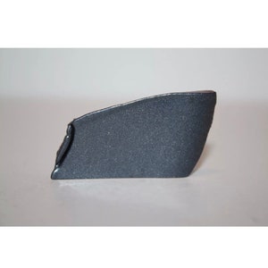 May include: A dark gray plastic car part with a textured surface.