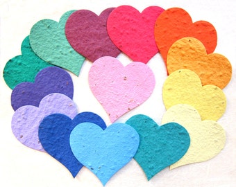 May include: A set of 10 paper heart seed packets in various colors, including green, purple, pink, orange, yellow, and blue. The hearts are arranged in a circle.