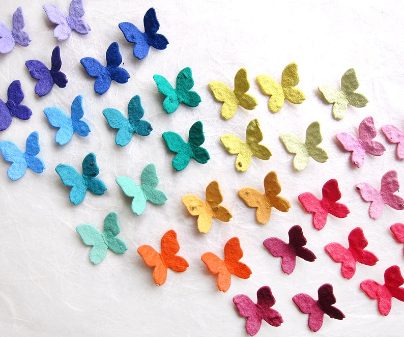Puede incluir: Un arco&iacute;ris de mariposas de papel de colores dispuestas en un degradado. Las mariposas est&aacute;n hechas de papel reciclado y son perfectas para a&ntilde;adir un toque de fantas&iacute;a a cualquier proyecto de manualidades.