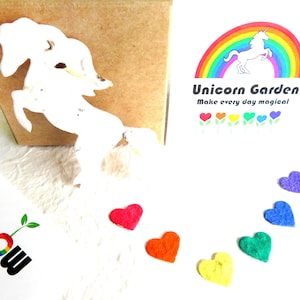 May include: A white unicorn paper craft with a rainbow and the text "Unicorn Garden Make every day magical" on a white background. There are seven rainbow-colored heart-shaped paper crafts below the unicorn.