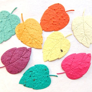 May include: A collection of eight leaf-shaped cutouts made from textured, fibrous paper in various colors including teal, orange, yellow, cream, purple, and pink. Each paper leaf features a stitched vein pattern running through the center.