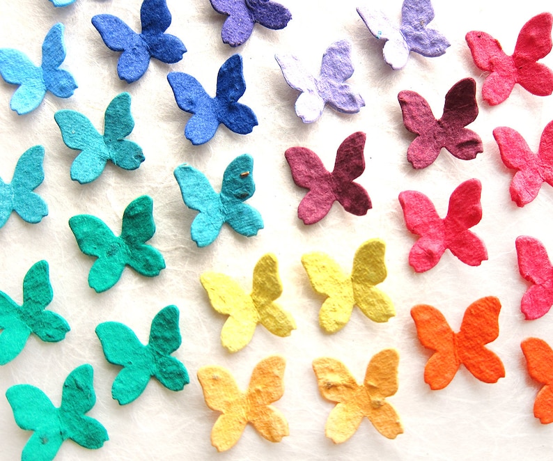Puede incluir: Surtido de mariposas de papel de colores en varios tonos de azul, verde, amarillo, naranja, rojo y morado. Las mariposas est&aacute;n hechas de papel reciclado y son perfectas para agregar un toque de fantas&iacute;a a cualquier proyecto artesanal.