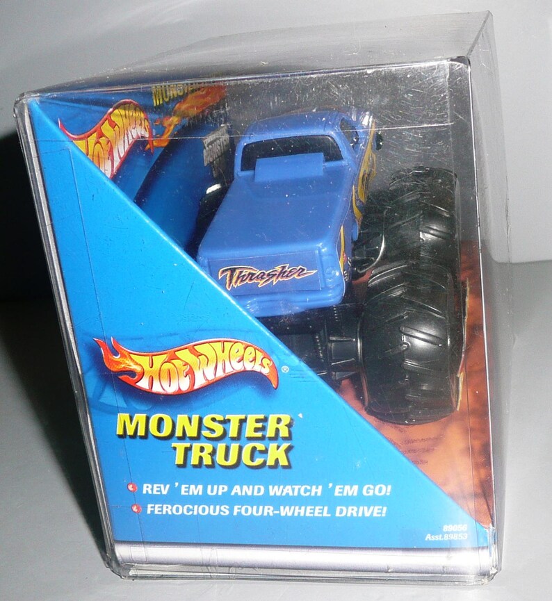Może przedstawiać: Niebieski Monster Truck Hot Wheels w przezroczystym plastikowym opakowaniu. Ciężar&oacute;wka ma czarne koła i napis "Thrasher" nadrukowany na boku. Opakowanie zawiera napis "Monster Truck" oraz "Rev 'em up and watch 'em go! Ferocious four-wheel drive!"