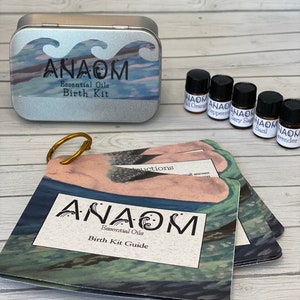 May include: A silver tin with the text "ANAOM Essential Oils Birth Kit" and a wave design. The image also shows small bottles of essential oils and a booklet titled "ANAOM Essential Oils Birth Kit Guide."