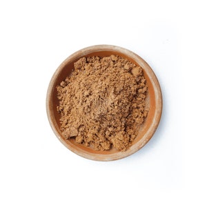 May include: A small terracotta bowl filled with a mound of brown ground spices.