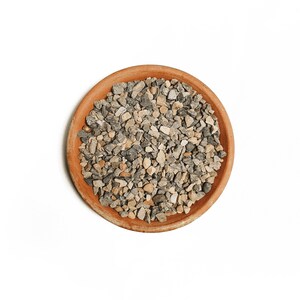May include: A terracotta pot filled with small, grey and beige gravel.