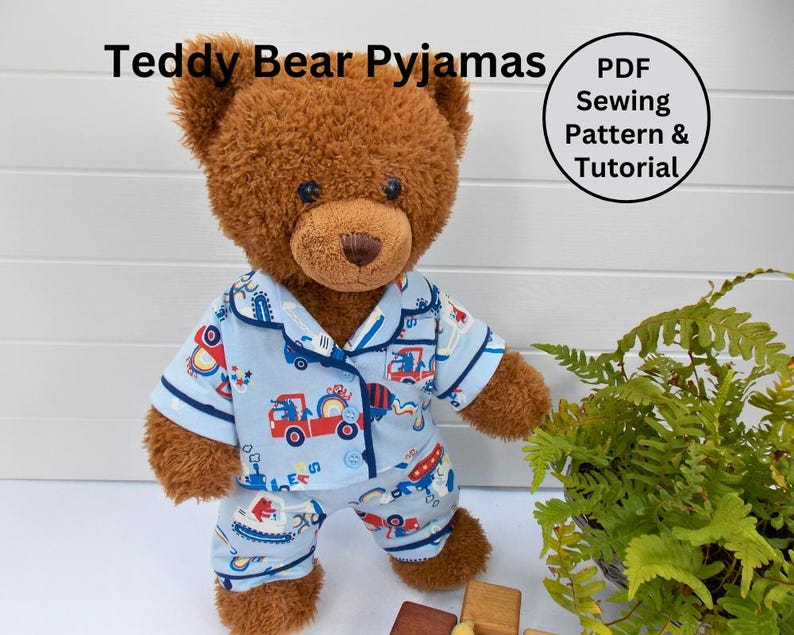 K&ouml;nnte beinhalten: Ein brauner Teddyb&auml;r tr&auml;gt einen blauen Schlafanzug mit einem Baufahrzeug-Druck. Der Schlafanzug hat einen Knopfleisten vorne und lange &Auml;rmel. Der Text "PDF Sewing Pattern & Tutorial" befindet sich in einem schwarzen Kreis auf wei&szlig;em Hintergrund.