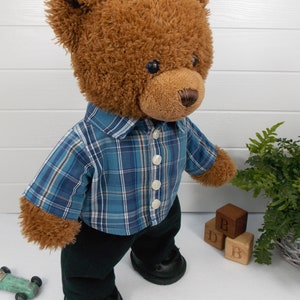 Build a bear teddy bear wearing a blue checked shirt and black trousers.