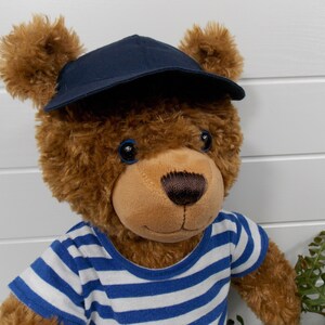 Build a bear teddy bear wearing a blue baseball cap and a blue and white t-shirt