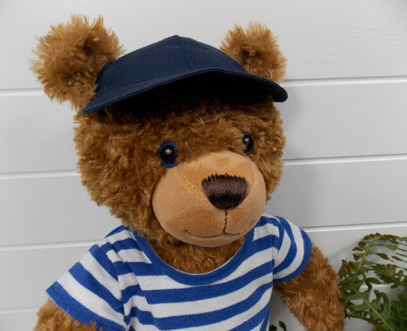 Build a bear teddy bear wearing a blue baseball cap and a blue and white t-shirt