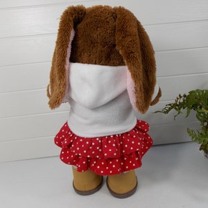 Build a bear teddy bear wearing a white hoodie, a red and white spotted skirt, white tights and sand coloured boots.