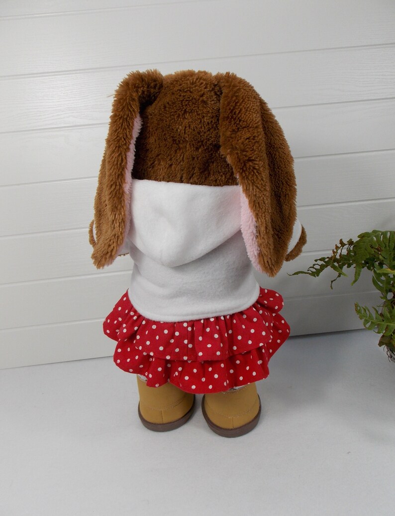 Build a bear teddy bear wearing a white hoodie, a red and white spotted skirt, white tights and sand coloured boots.