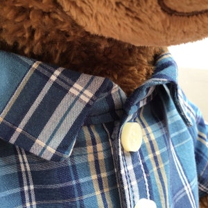 Close up of a blue checked shirt with white buttons worn by a build a bear teddy bear.