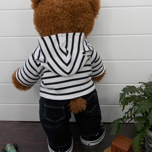 Build a bear teddy bear wearing a black and white striped hoodie, black jeans and black and white converse trainers.