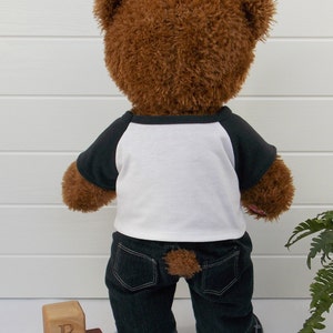 Build a bear teddy bear wearing a black and white t-shirt, black jeans and black and white converse trainers.