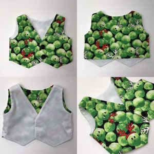 May include: A reversible vest with a green and white pattern of Brussels sprouts with red reindeer antlers. One side of the vest is white with a green pattern, and the other side is black with a green pattern.