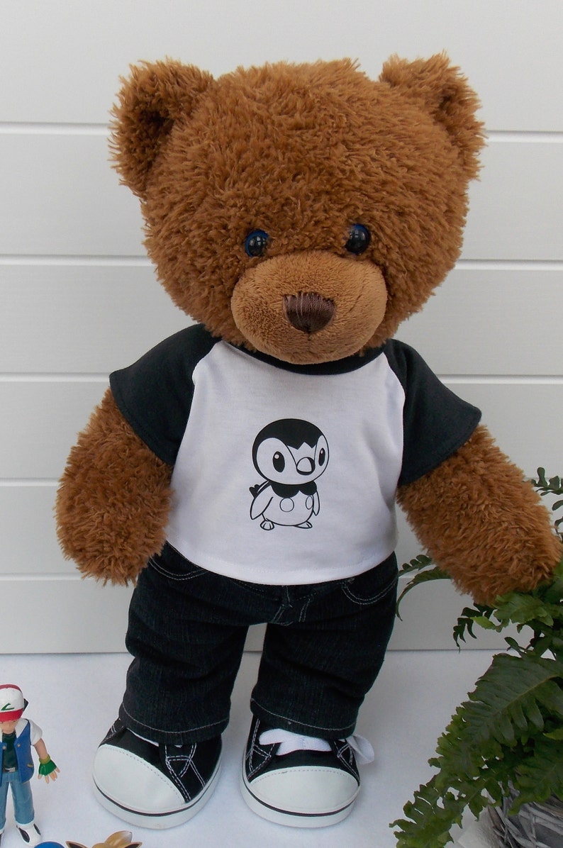 Build a bear teddy bear wearing a black and white t-shirt with a Pokemon figure (Piplup) on the front, black jeans and black and white converse trainers.
