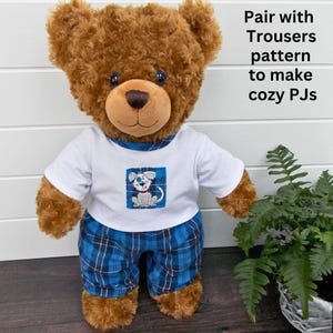 Brown Build-a-Bear teddy bear wearing teddy bear pyjamas. The teddy bear pyjamas have been made with a sewing pattern from Best Dressed Bears. The pyjamas trousers are made from blue checked fabric and the pyjama top is white fabric with a blue dog patch sewn on.