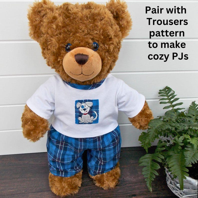 Brown Build-a-Bear teddy bear wearing teddy bear pyjamas. The teddy bear pyjamas have been made with a sewing pattern from Best Dressed Bears. The pyjamas trousers are made from blue checked fabric and the pyjama top is white fabric with a blue dog patch sewn on.