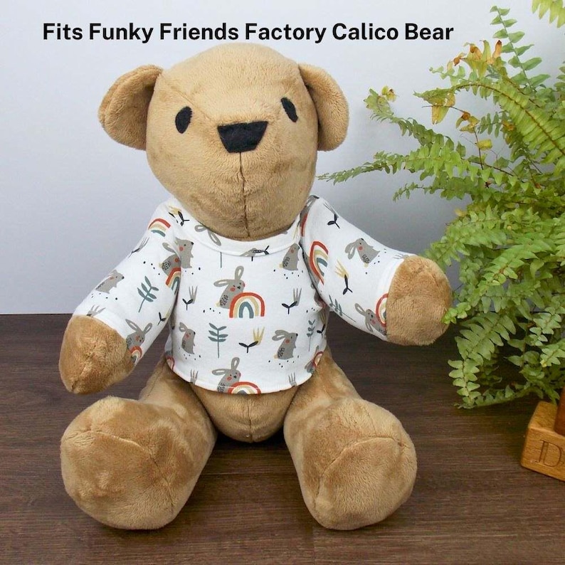Brown Funky Friends Factory Calico teddy bear wearing a white patterned t-shirt. The text on the image reads 'Fits Funky Friends Factory Calico Bear' refers to the fact that the t-shirt the teddy is wearing is made with a sewing pattern from Best Dressed Bears
