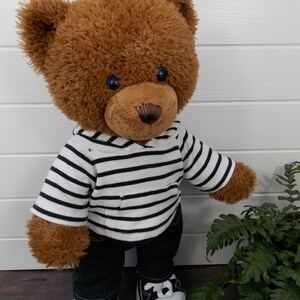Build a bear teddy bear wearing a black and white striped hoodie, black jeans and black and white converse trainers.