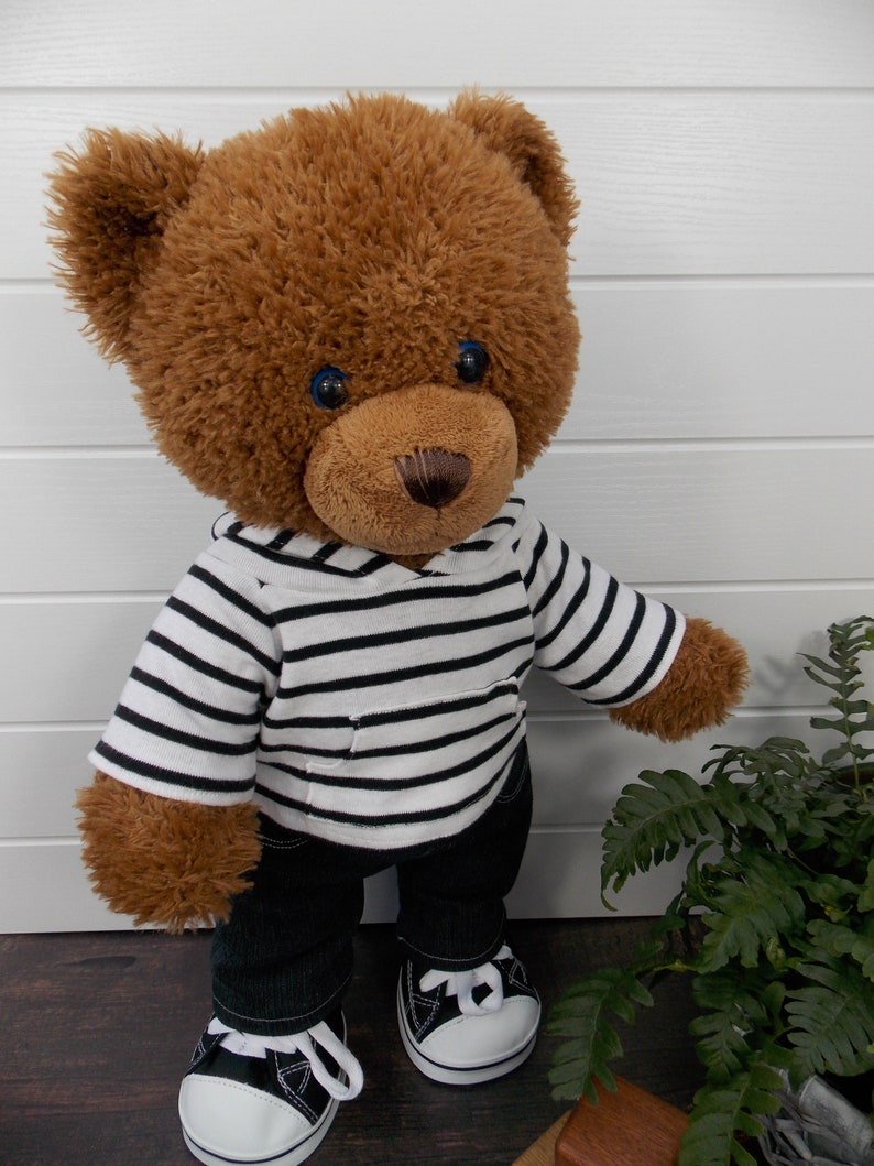 Build a bear teddy bear wearing a black and white striped hoodie, black jeans and black and white converse trainers.
