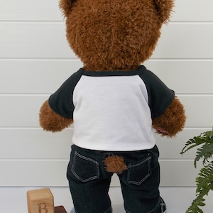 Build a bear teddy bear wearing a black and white t-shirt, black jeans and black and white converse style trainers.