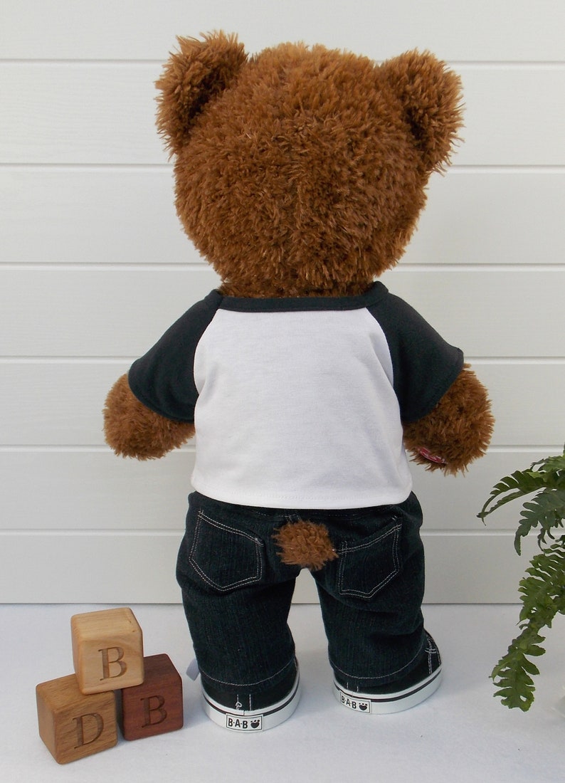 Build a bear teddy bear wearing a black and white t-shirt, black jeans and black and white converse style trainers.