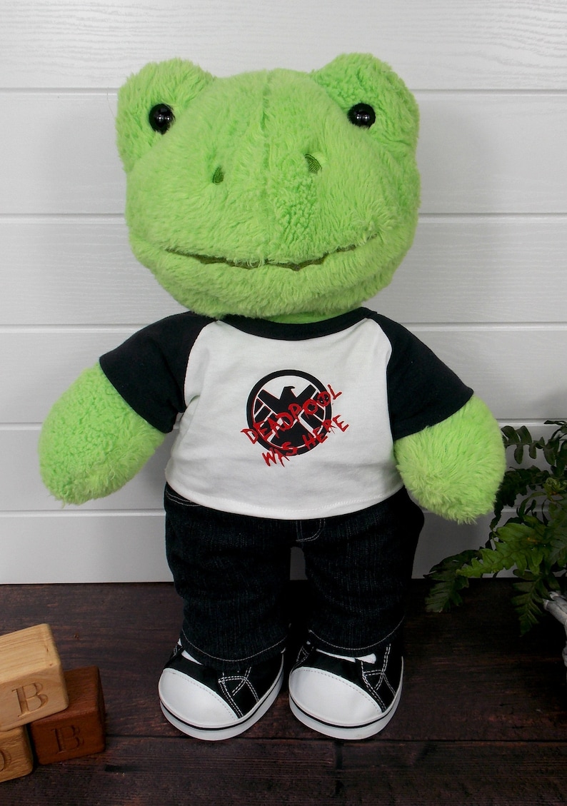 Build a bear frog wearing a black and white t-shirt, black jeans and black and white converse style trainers.