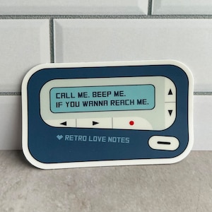 May include: A blue and white sticker of a vintage pager with the text "CALL ME. BEEP ME. IF YOU WANNA REACH ME." and the words "RETRO LOVE NOTES" below the screen.