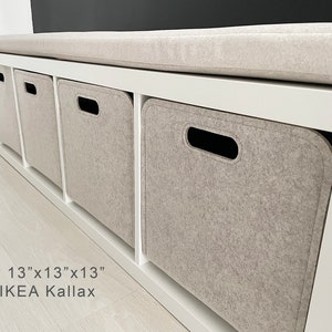 May include: A white storage bench with four cubbies, each containing a light gray felt storage bin. The bench has a light gray cushioned top. The text on the image reads "SIZE 13"x13"x13" for IKEA Kallax."