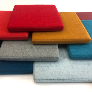 May include: A stack of nine square fabric tiles in various colors, including red, orange, gray, blue, and pink. The tiles are made of a soft, textured material and have a subtle sheen.