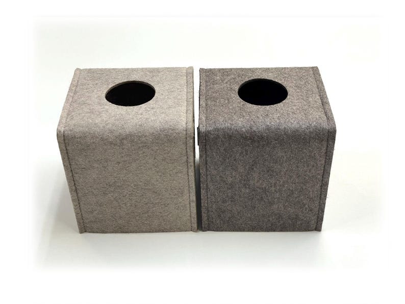 May include: Two square tissue box covers made of felt. One is light beige, the other is gray. Each has a circular opening on top for tissue dispensing. The boxes are side-by-side against a white background.