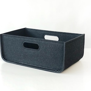 May include: A rectangular, dark gray felt storage bin with two handle cutouts. The bin is designed with a simple, modern aesthetic, suitable for organizing various items. The felt material provides a soft, textured appearance.