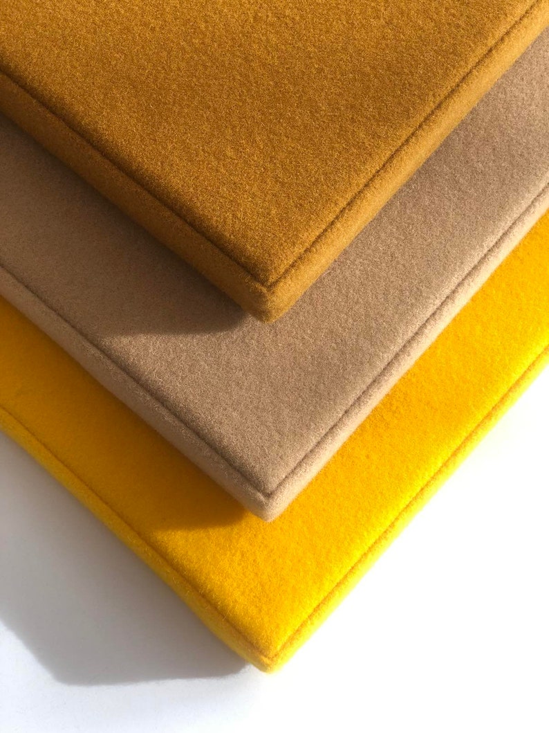 May include: Three fabric squares stacked on top of each other. The top square is a mustard yellow color, the middle square is a light brown color, and the bottom square is a bright yellow color.