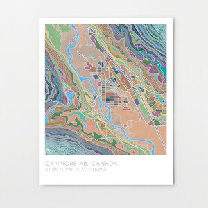 May include: A colorful abstract map of Canmore, AB, Canada. The map features a variety of colors and shapes, including blue, green, purple, and orange. The map is surrounded by a white border and includes the text "Canmore AB, Canada" and the coordinates "51.05'21.9"N 115.21'38.0"W".