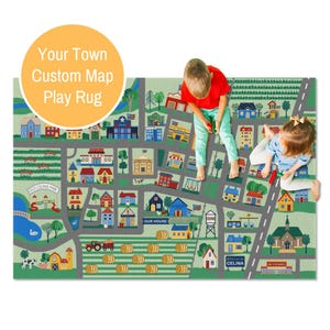 May include: A custom play rug featuring a town map design with buildings, roads, and green spaces. The rug includes the text "Your Town Custom Map Play Rug". Two children are sitting on the rug.